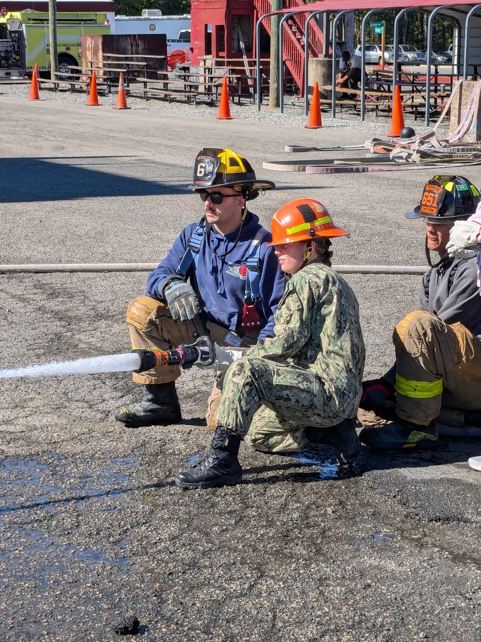 AMERICA Division cadet operating a fire hose with instructor coaching during firefighting training