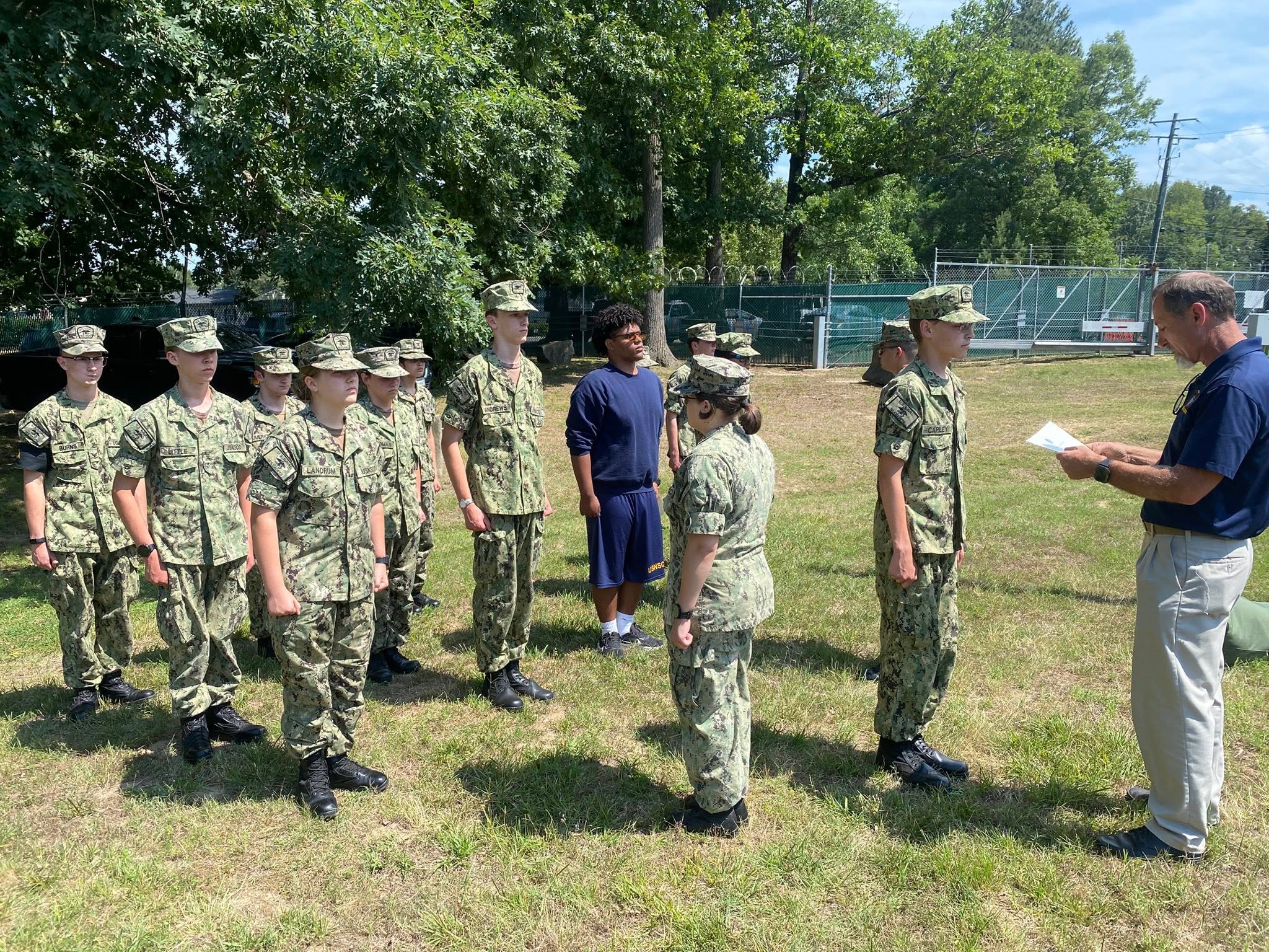 Adult officer leading Sea Cadets in outdoor formation at the Richmond NOSC