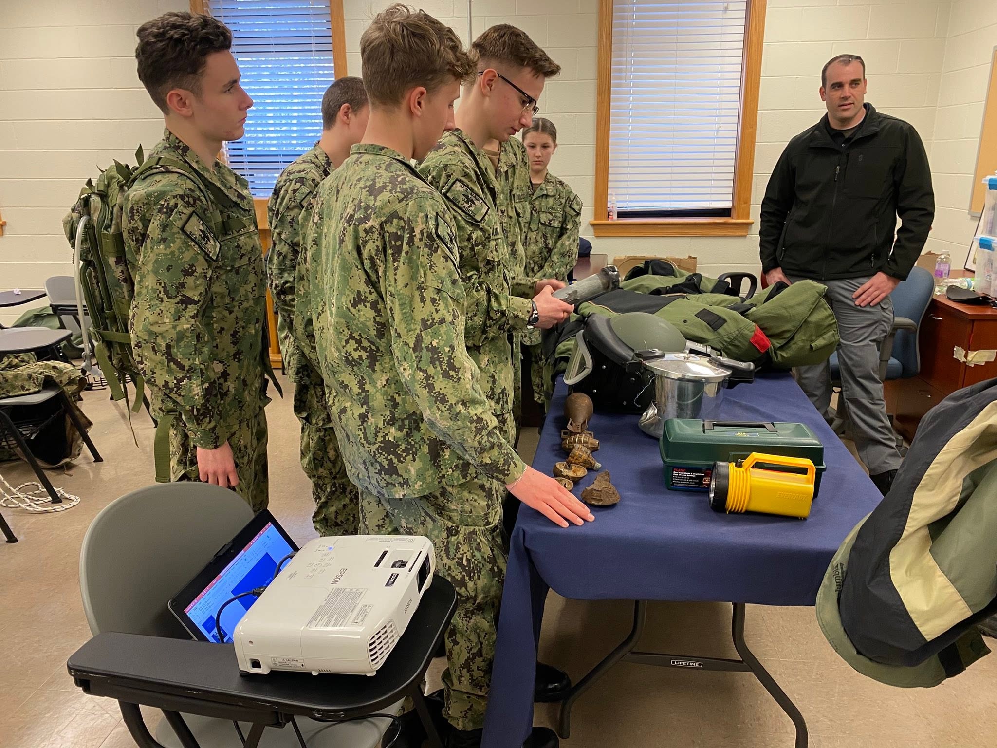 Cadets examining EOD equipment at a table with an instructor