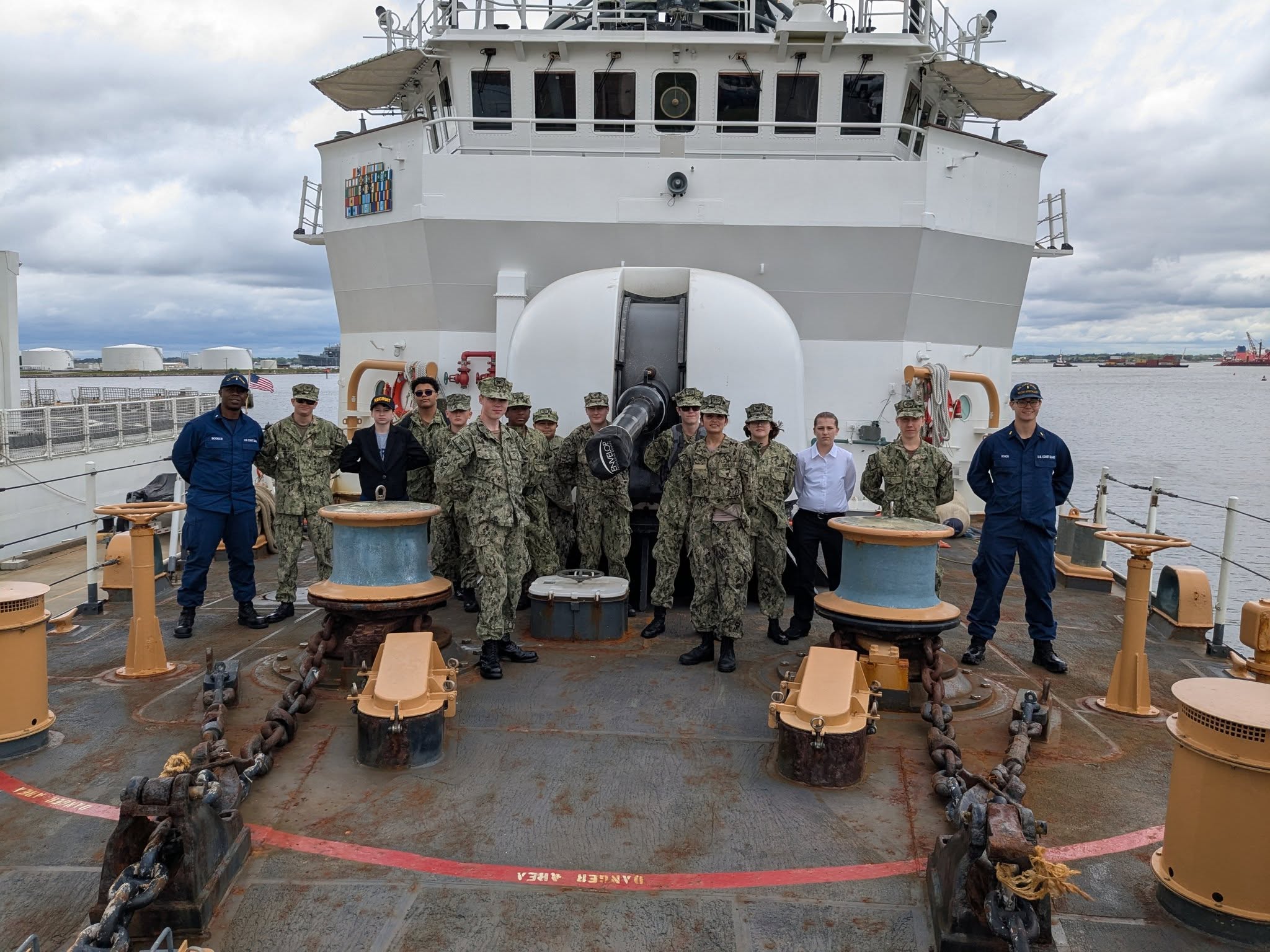 Cadets on the deck of a Coast Guard cutter with harbor in background