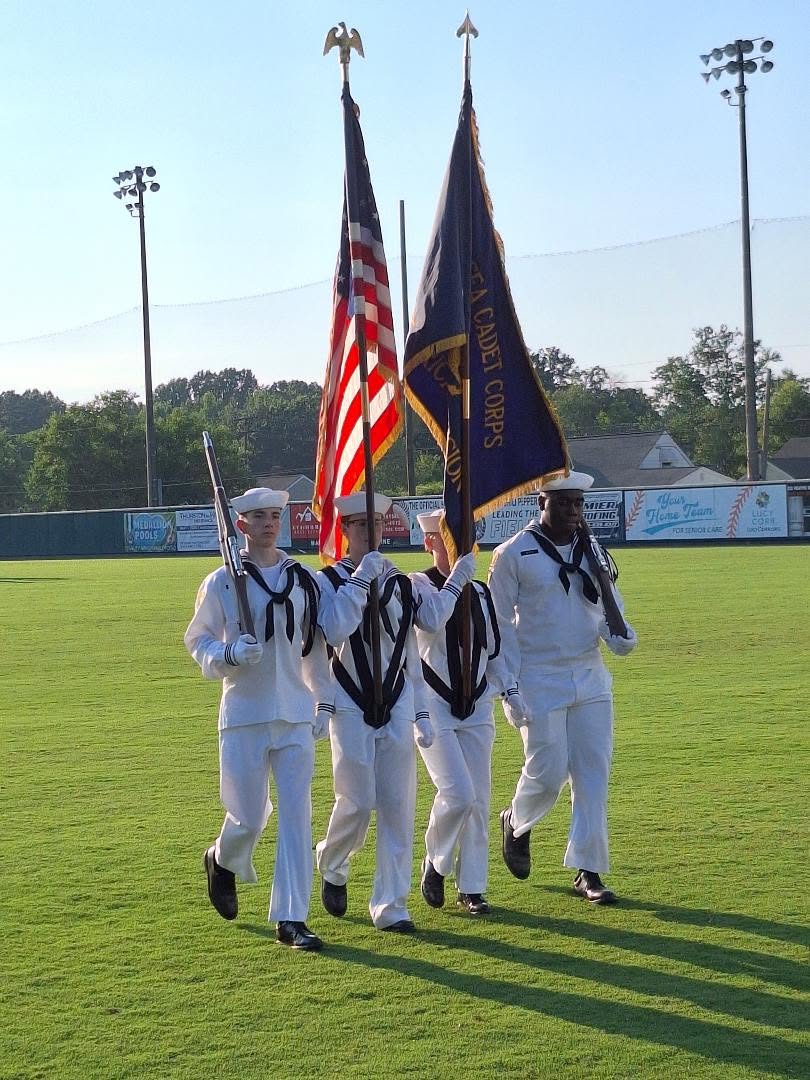 America Division color guard in white dress uniforms marching at golden hour