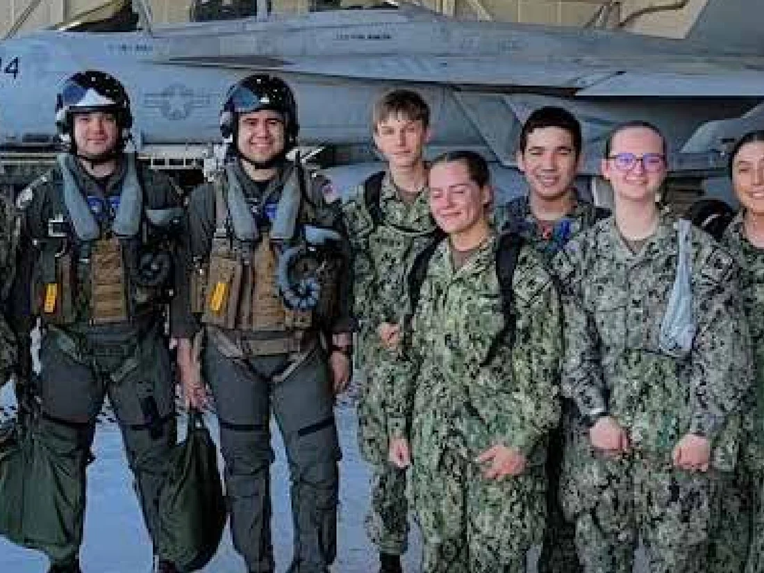 Sea Cadets in flight gear with a Navy fighter jet during Airman Training